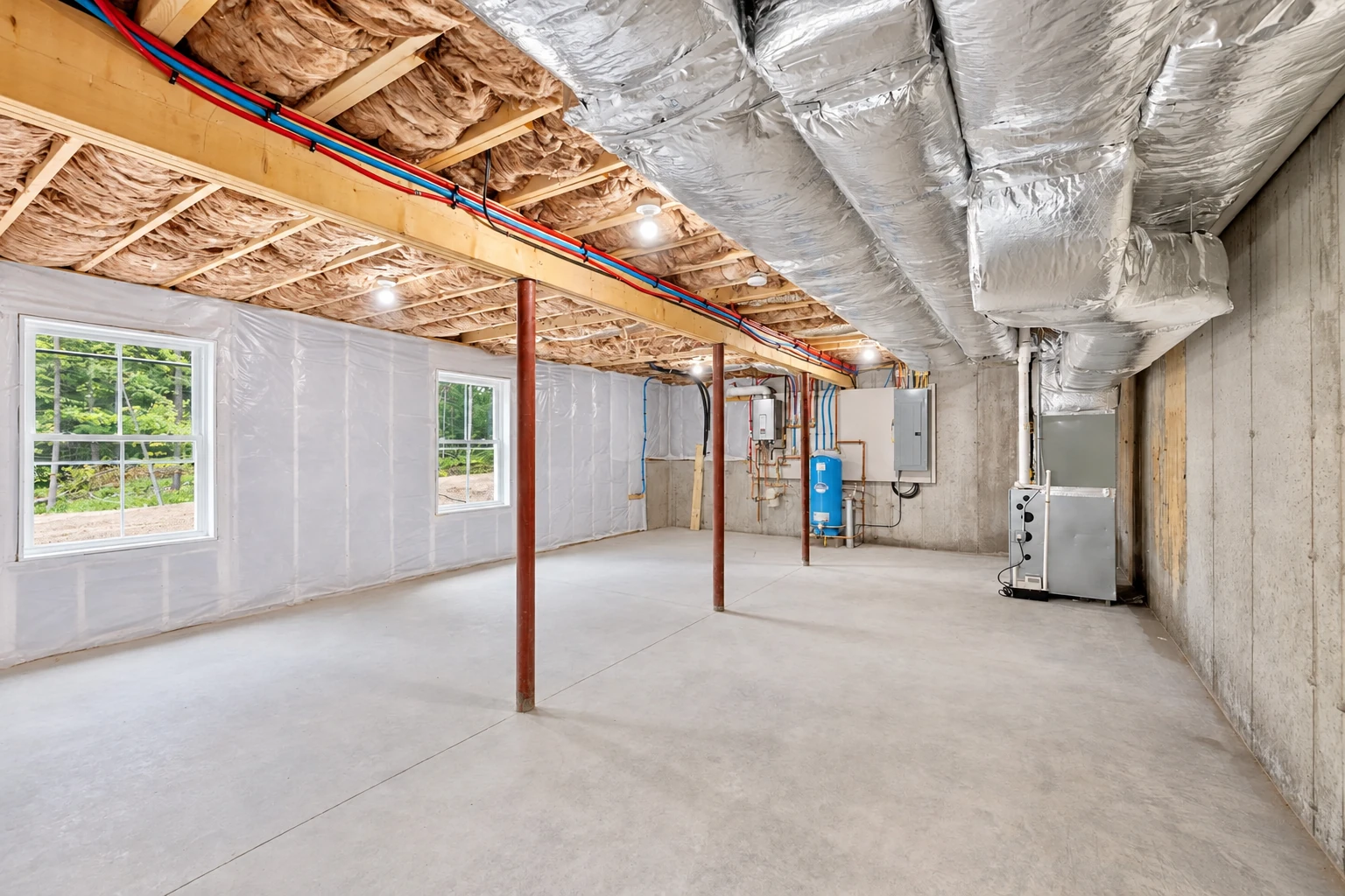 Unfinished basement with silver ductwork overhead, fiberglass insulation between floor joists, and plastic-covered walls.